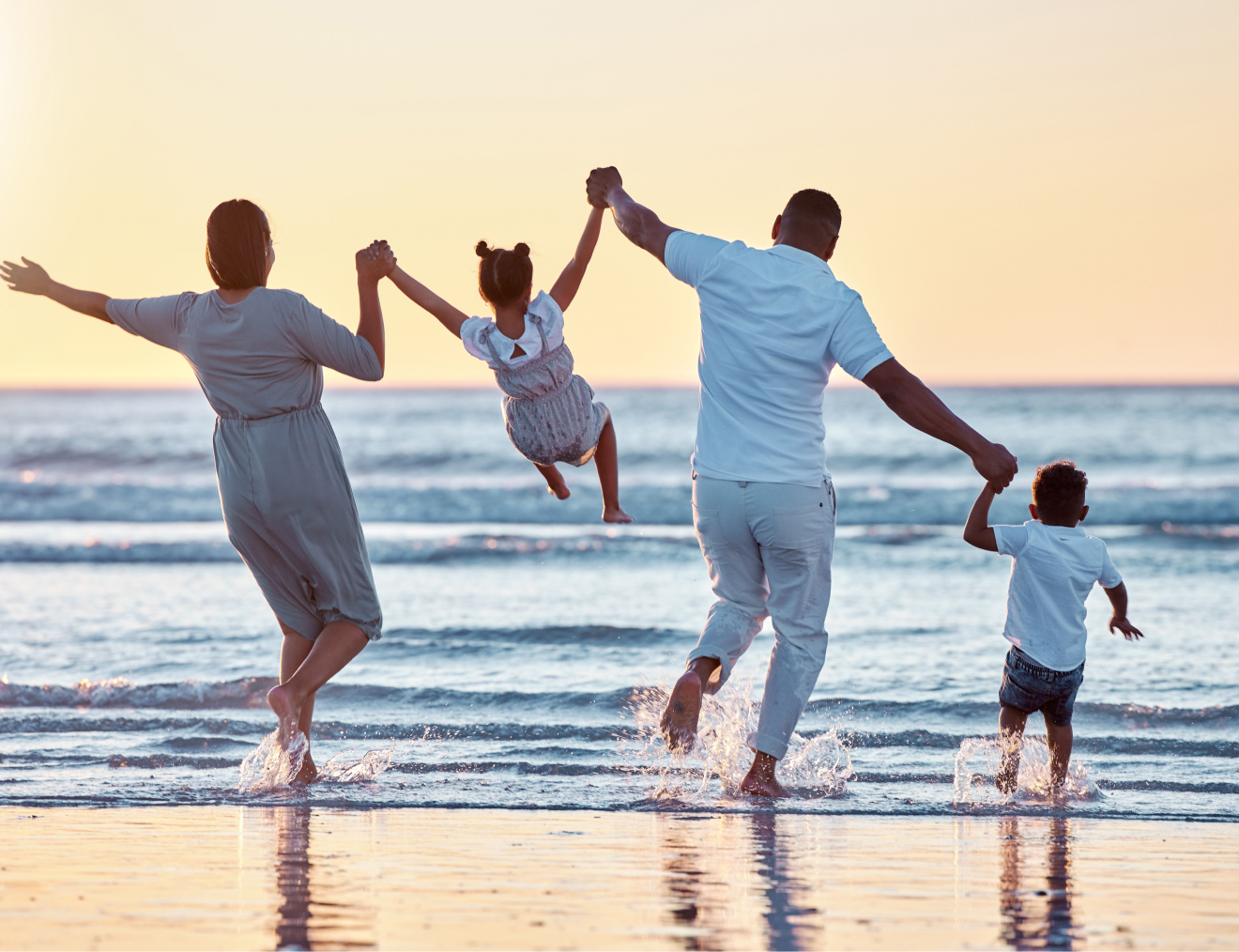 Family playing in the sea at sunset