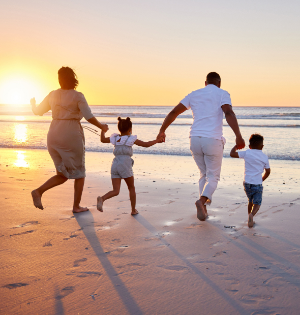 Family running along the beach at sunset