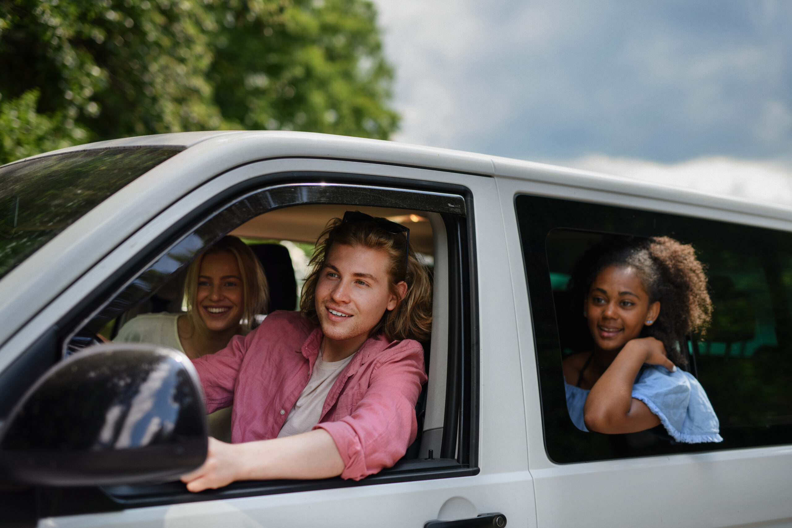 Young women smiling from the windows of a car